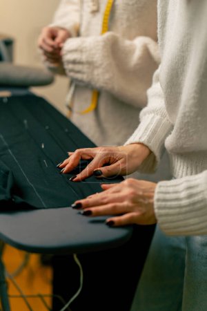 Foto de De cerca en un taller de costura costurera alfileres de un alfiler corrugado en un tejido negro - Imagen libre de derechos