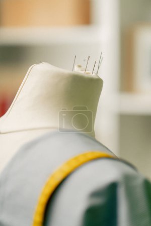 close-up in a sewing workshop of a mannequin with pins with a blue cloth thrown over it and a centimeter and