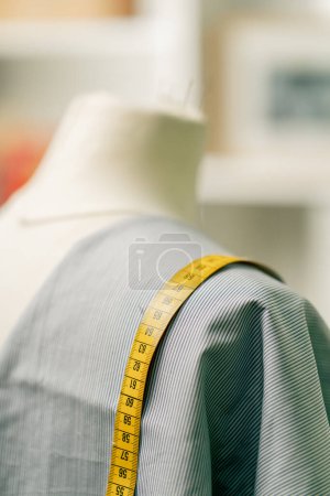 close-up of a mannequin in a sewing workshop with a blue cloth draped over it and a centimeter