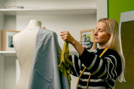 in a sewing workshop a seamstress works with a mannequin applying green fabric