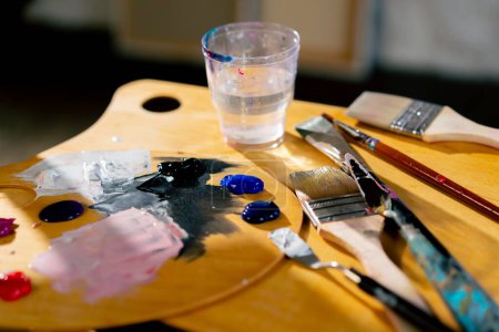 Foto de Primer plano en un taller de arte hay una paleta en un cuchillo de paleta taburete un vaso de disolvente - Imagen libre de derechos