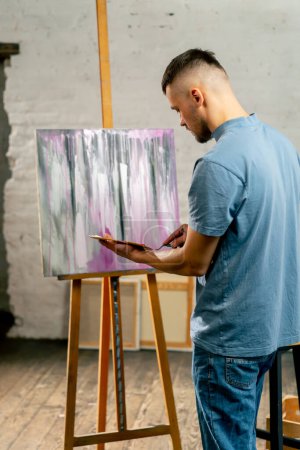 Téléchargez les photos : In an art studio an artist mixes color on a palette holding in his hands - en image libre de droit