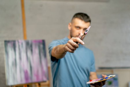 Foto de En un estudio de arte un artista toma medidas a ojo con un cuchillo paleta directamente en la cámara - Imagen libre de derechos