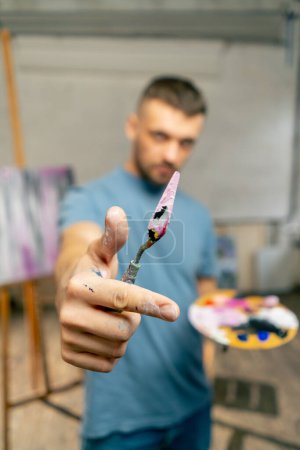 Photo for In an art studio an artist takes measurements by eye with a palette knife directly into the camera - Royalty Free Image