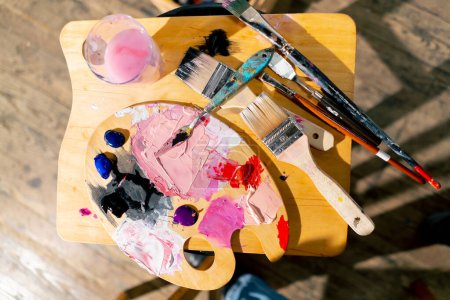 Photo for Close-up top shot in an art workshop there is a palette on a stool palette knife a glass of solvent - Royalty Free Image