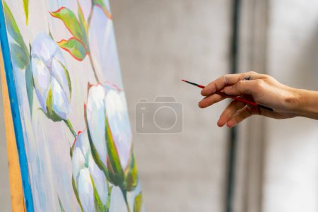 Téléchargez les photos : Gros plan dans un atelier d'art des mains sales d'un artiste peignant des détails sur toile avec un pinceau - en image libre de droit