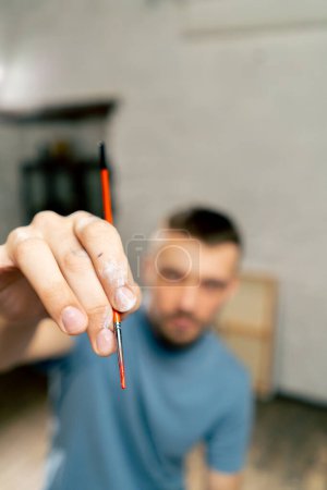 Foto de Primer plano en un estudio de arte de un artista manos con un cepillo hacia la cámara - Imagen libre de derechos