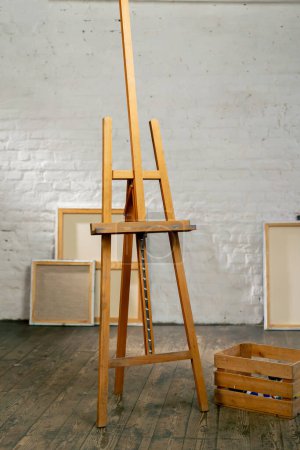 Foto de En un estudio de arte hay un trípode sobre un fondo de lienzos junto a una caja - Imagen libre de derechos