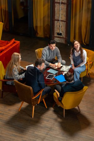 Photo for Top shot in a large beautiful hall office employees sitting on yellow chairs discuss a deal - Royalty Free Image