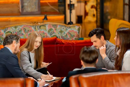 Photo for In the recreation area sitting on yellow chairs office employees a girls and guys plan their work schedule - Royalty Free Image