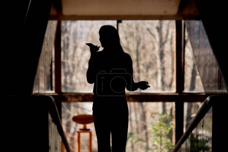 Photo for In the office on the landing overlooking the window in the back light a girl speaks on the phone - Royalty Free Image