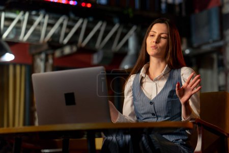 en la oficina en una silla amarilla en una mesa de madera chica de oficina llamando a la reunión a través de la computadora portátil