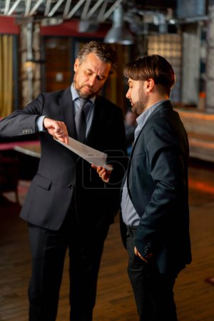 Photo for In the office the director and an employee are standing discussing amendments to the contract - Royalty Free Image