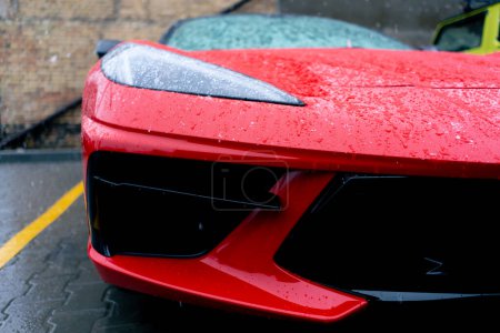 Foto de Primer plano de los faros de un coche deportivo rojo claro parado en la calle mojado después de la nieve - Imagen libre de derechos