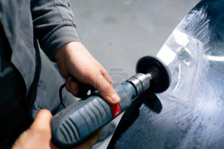 Nahaufnahme an einer Tankstelle: Ein Automechaniker versucht, einen Teil des Autos zu schleifen