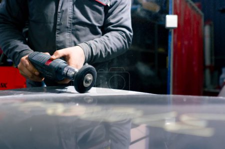 Nahaufnahme an einer Tankstelle: Ein Automechaniker versucht, einen Teil des Autos zu schleifen