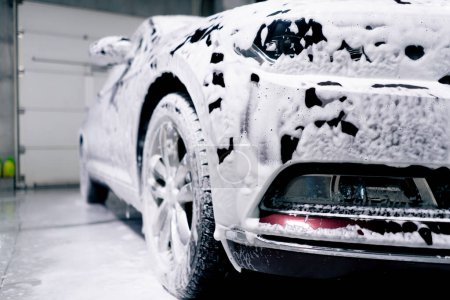 Photo for Close-up at a service station in a car wash booth the process of soaping a car with foam - Royalty Free Image