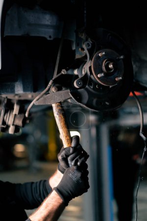 Foto de Primer plano en una estación de servicio en el pabellón un mecánico automático martillos en pernos en una llanta de coche - Imagen libre de derechos