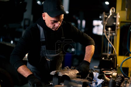 Photo for At a service station an auto mechanic works on a car part before installation - Royalty Free Image