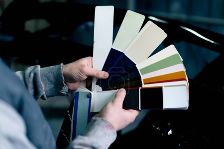 Foto de Primer plano de la mano en una estación de servicio un maestro selecciona un color de pintura en una paleta de colores - Imagen libre de derechos