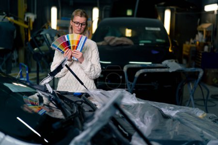 Foto de Niñas en la estación de servicio elegir un color de pintura en una paleta de papel de color sobre el fondo de su coche - Imagen libre de derechos