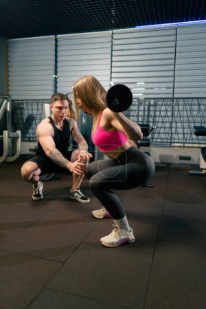 Photo for In pair training the coach and the girl coach controls the work of lifting the barbell - Royalty Free Image