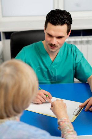 Téléchargez les photos : Consultation entre un médecin et un patient âgé dans une clinique de chirurgie plastique - en image libre de droit