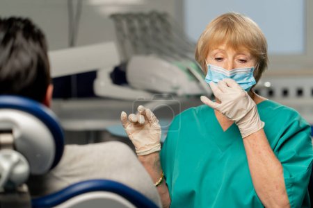 Photo for In dental clinic an orthodontist adjusts a mask before examining a patient - Royalty Free Image