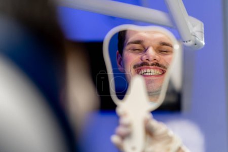 Téléchargez les photos : Close-up in a dental clinic the dentist shows the result to the patient through the mirror - en image libre de droit