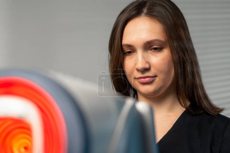 Photo for Close up in an ophthalmology clinic a female doctor performs a diagnosis using a device with a red light - Royalty Free Image