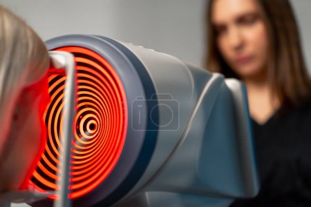 Téléchargez les photos : Gros plan dans une clinique d'ophtalmologie une femme médecin effectue des diagnostics à l'aide d'un dispositif avec rouge - en image libre de droit
