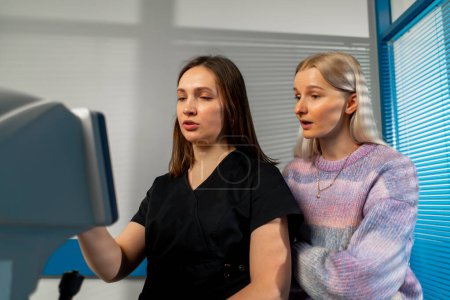 Photo for In an ophthalmology clinic a female doctor shows the patient and tells the diagnostic results - Royalty Free Image