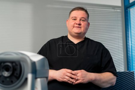 Photo for In an ophthalmology clinic obese doctor says the results of eye diagnostics and smiles - Royalty Free Image