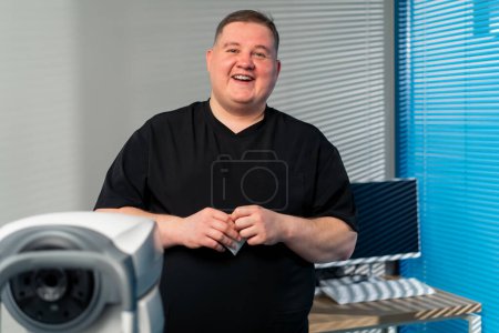 Téléchargez les photos : Dans une clinique d'ophtalmologie médecin obèse dit les résultats de diagnostics oculaires et sourires - en image libre de droit