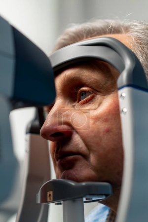 Foto de Primer plano en la clínica de oftalmología paciente de edad avanzada se diagnostica con una prueba de visión utilizando la máquina - Imagen libre de derechos