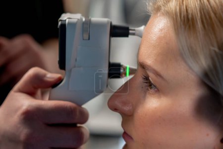 Photo for Close up in an ophthalmology clinic a young girl is checking the pressure of the eyeball - Royalty Free Image