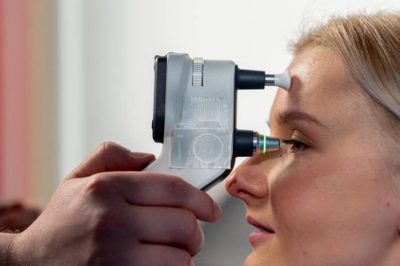Photo for Close up in an ophthalmology clinic a young girl is checking the pressure of the eyeball - Royalty Free Image