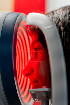 Téléchargez les photos : Gros plan dans une clinique d'ophtalmologie une petite fille diagnostique la vision avec une machine à lumière rouge - en image libre de droit