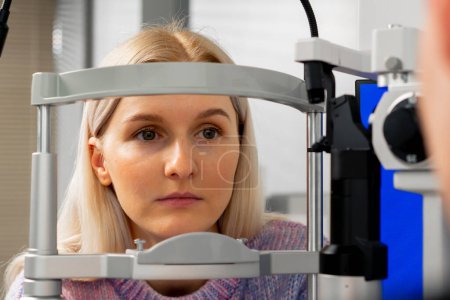 Téléchargez les photos : Gros plan dans une clinique d'ophtalmologie une jeune fille communique avec un médecin grâce à une machine de diagnostic - en image libre de droit