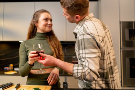 Téléchargez les photos : Jeune couple amoureux dans la belle cuisine préparer le dîner ensemble et boire du vin - en image libre de droit