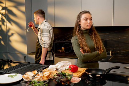 Téléchargez les photos : Jeune couple amoureux dans une belle cuisine cuisiner ensemble conflit humeur négative querelle - en image libre de droit