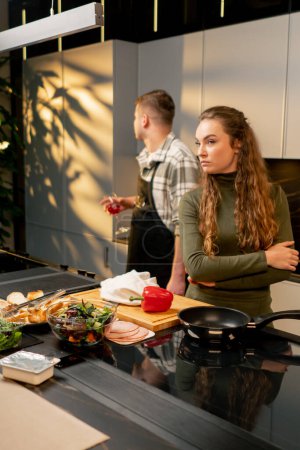 Téléchargez les photos : Jeune couple amoureux dans une belle cuisine cuisiner ensemble conflit humeur négative querelle - en image libre de droit