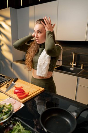 Foto de Jovencita enamorada en un vestido verde en la cocina preparando la cena cansada después del trabajo - Imagen libre de derechos