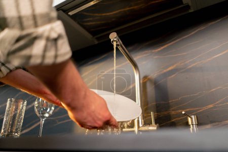 Téléchargez les photos : Gros plan d'un jeune amoureux dans la cuisine qui lave la vaisselle après le dîner - en image libre de droit