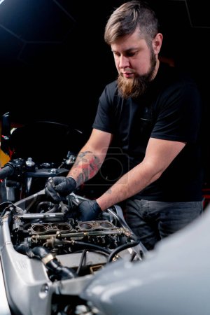 Dans un atelier de réparation de motos, un maître s'occupe du câblage du système moteur.