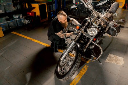 Dans un atelier de réparation de moto, un maître répare une moto et met à jour les systèmes d'alimentation en carburant