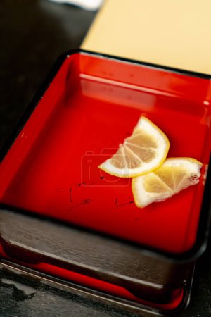 Téléchargez les photos : Dans un restaurant japonais, des tranches de lime tranchées sont placées dans un récipient en fer rouge. - en image libre de droit