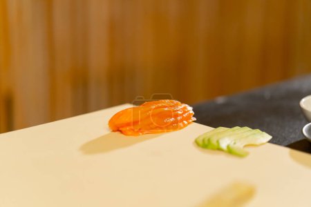 Photo for Close-up in a Japanese restaurant sliced fish and avocado on a white board for a dish - Royalty Free Image