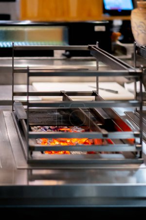 Téléchargez les photos : Close-up dans un restaurant japonais grill de table compact pour la cuisson des aliments charbons à haute température - en image libre de droit