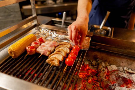 Téléchargez les photos : Gros plan dans un restaurant japonais le chef grille divers légumes comme plat d'accompagnement pour le poisson - en image libre de droit